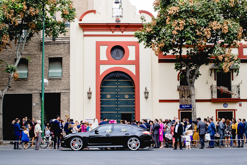 Coche de bodas Porsche Panamera GTS, en la puerta de una Boda en la Hermandad de los Negritos en Sevilla, fotografía por Moisés García para Bodas con Arte, fotógrafo de bodas en Sevilla Este.